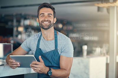 Buy stock photo Portrait of a young man using a digital tablet while working at a coffee shop
