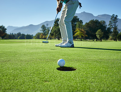 Buy stock photo Low angle shot of a unrecognizable man hitting a golfball into a hole on a golf course