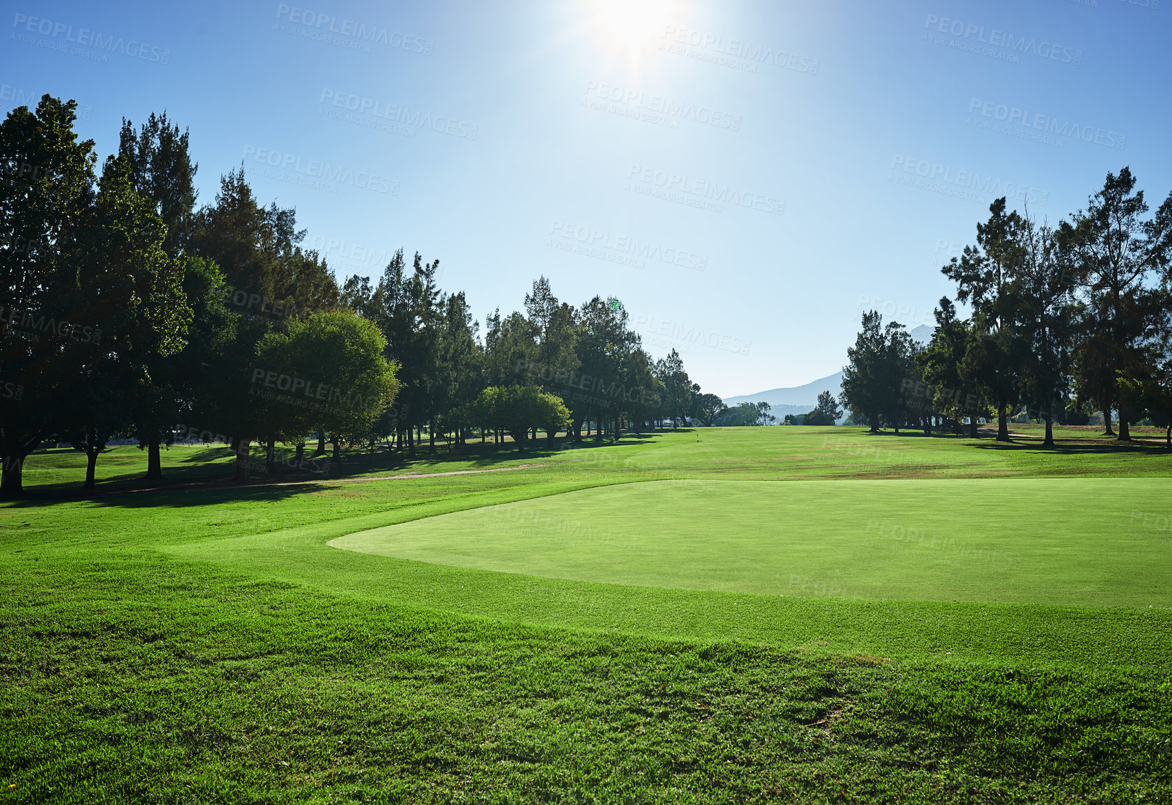 Buy stock photo Shot of a beautiful green golf course surrounded with trees on a sunny day