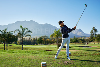 Buy stock photo Shot of a focused young man hitting a golfball on a golf course outside during the day