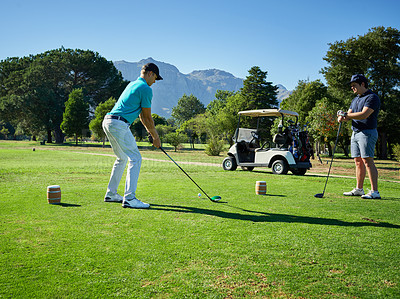 Buy stock photo Shot of two focused young men playing a game of golf outside on a golf course