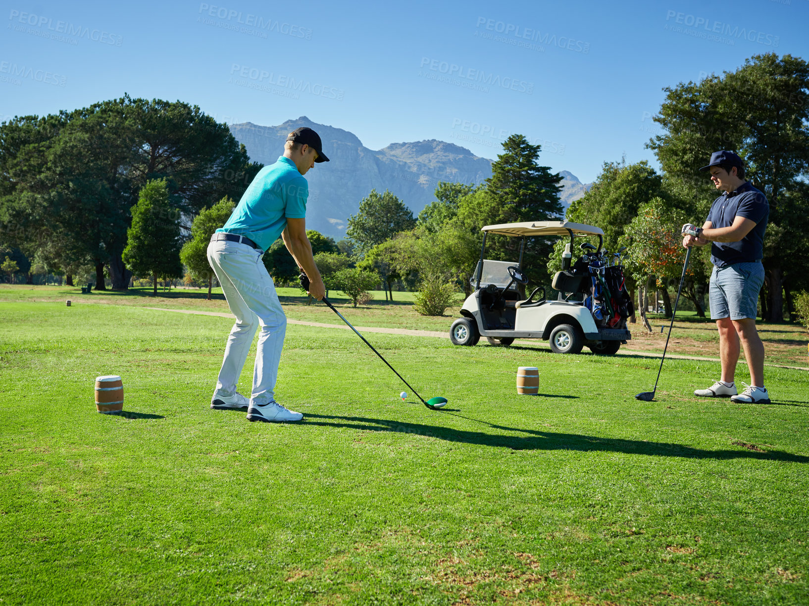 Buy stock photo Shot of two focused young men playing a game of golf outside on a golf course
