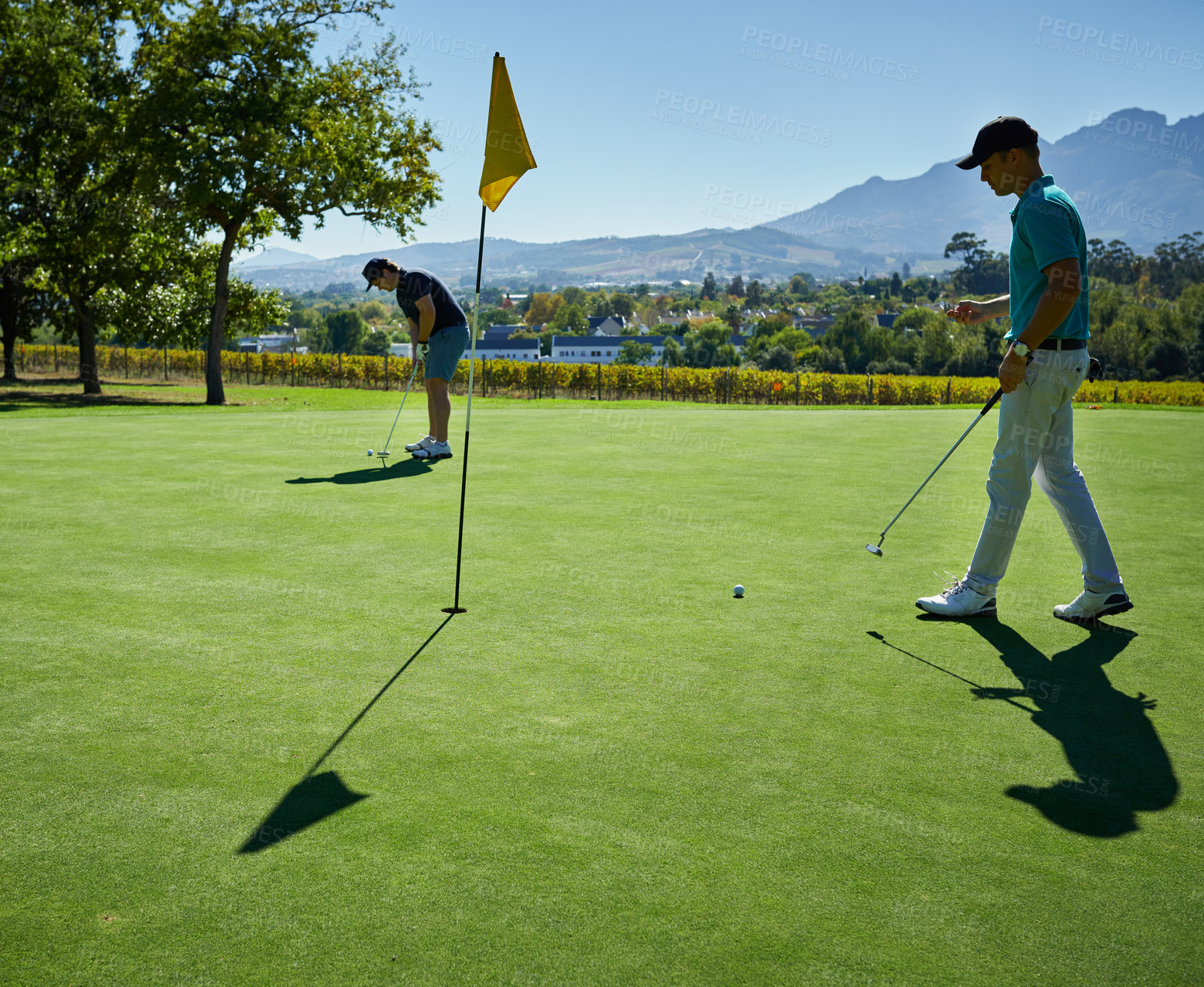 Buy stock photo Shot of two focused young men playing a game of golf outside on a golf course