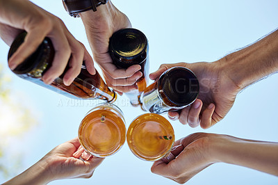 Buy stock photo Low angle shot of a young group of friends toasting while enjoying a few drinks outside in the summer sun