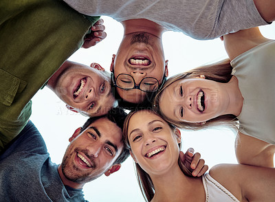 Buy stock photo Low angle portrait of a young group of friends standing outside in a huddle