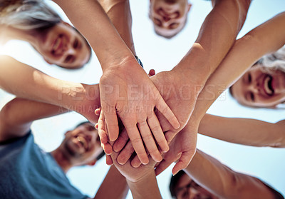 Buy stock photo Low angle shot of a young group of friends standing outside with their hands in a huddle