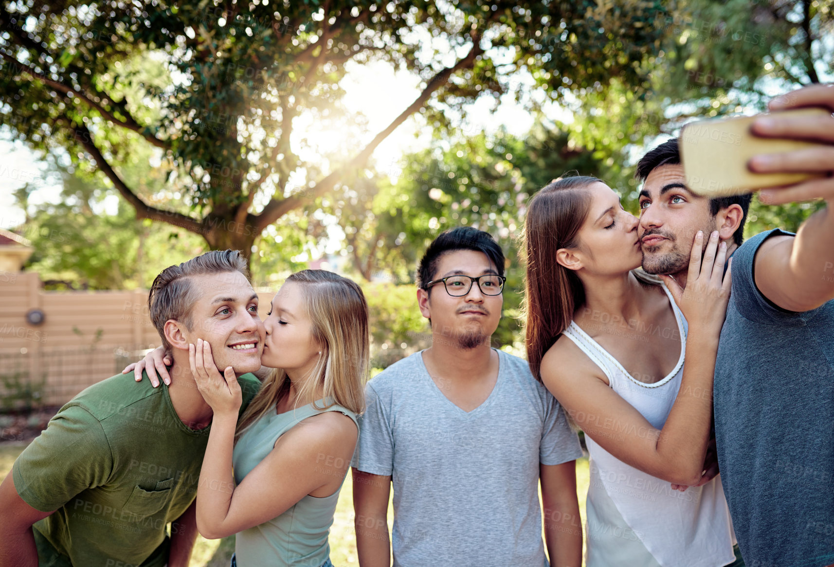 Buy stock photo Cropped shot of a young group of friends taking selfies while enjoying a few drinks outside in the summer sun