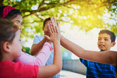 Buy stock photo Shot of a diverse group of young friends giving each other a high five outside