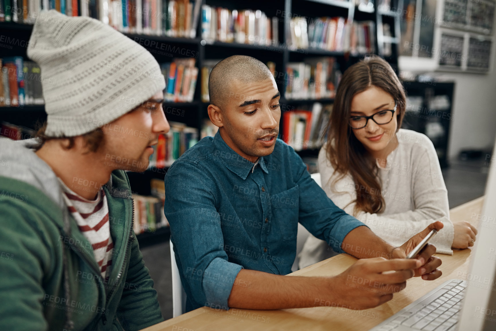 Buy stock photo High angle shot of three young university students studying in the library