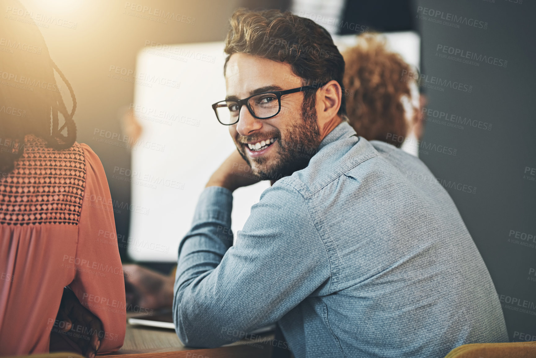 Buy stock photo Shot of a young businessman looking back during a meeting in the office