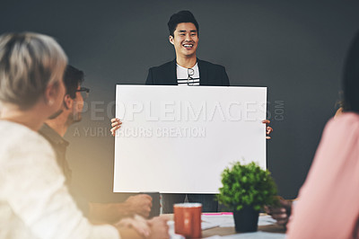 Buy stock photo Shot of a young businessman holding up a placard during a meeting inside