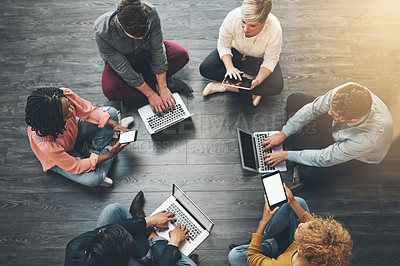 Buy stock photo Creative, modern group of casual business people, sitting with laptop and brainstorming on presentation meeting. Overhead view of team of employees sitting on office floor, working on ideas together