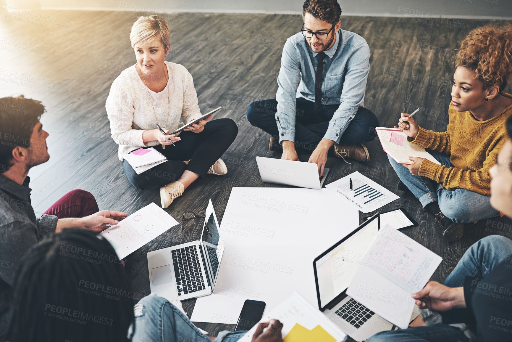 Buy stock photo Creative and busy business people working on strategy planning and brainstorming paper work or ideas at informal meeting from above view. Corporate marketing group collaborating on a digital project 