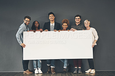 Buy stock photo A group of professionals holding a blank board or sign with copy space on a grey background. Diverse team advertising space or a vacancy at their startup. Smiling colleagues advertising on a placard