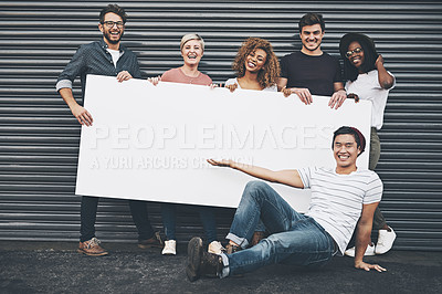 Buy stock photo Shot of a diverse group of people holding up a placard outside