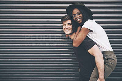 Buy stock photo Cute, loving and affectionate interracial couple having fun, being playful and enjoying time together on copy space background. Happy boyfriend giving young girlfriend a piggyback ride outside