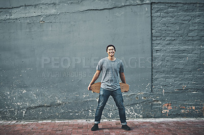 Buy stock photo Shot of a young man holding a skateboard outside