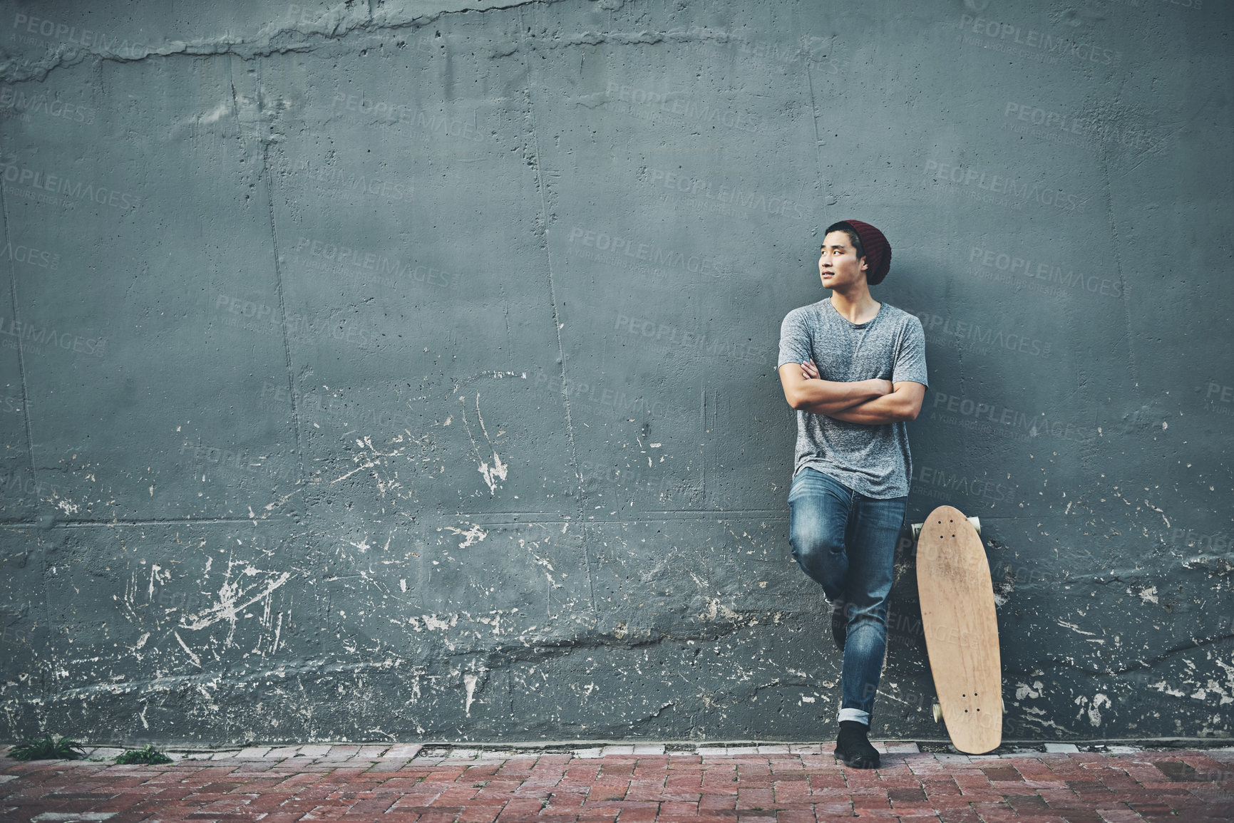 Buy stock photo Shot of a young man posing with a skateboard outside