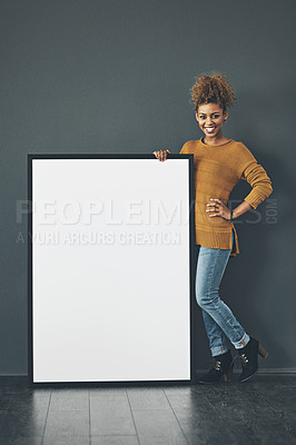 Buy stock photo Studio portrait of a young woman standing with a blank sign against a grey background