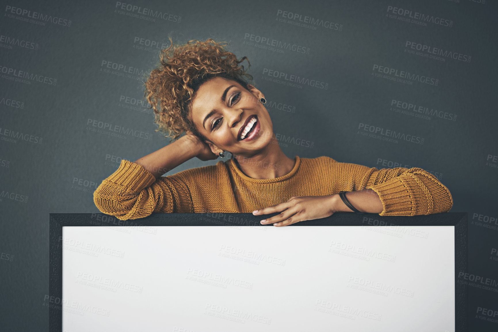 Buy stock photo Studio portrait of a young woman standing behind a blank sign against a grey background