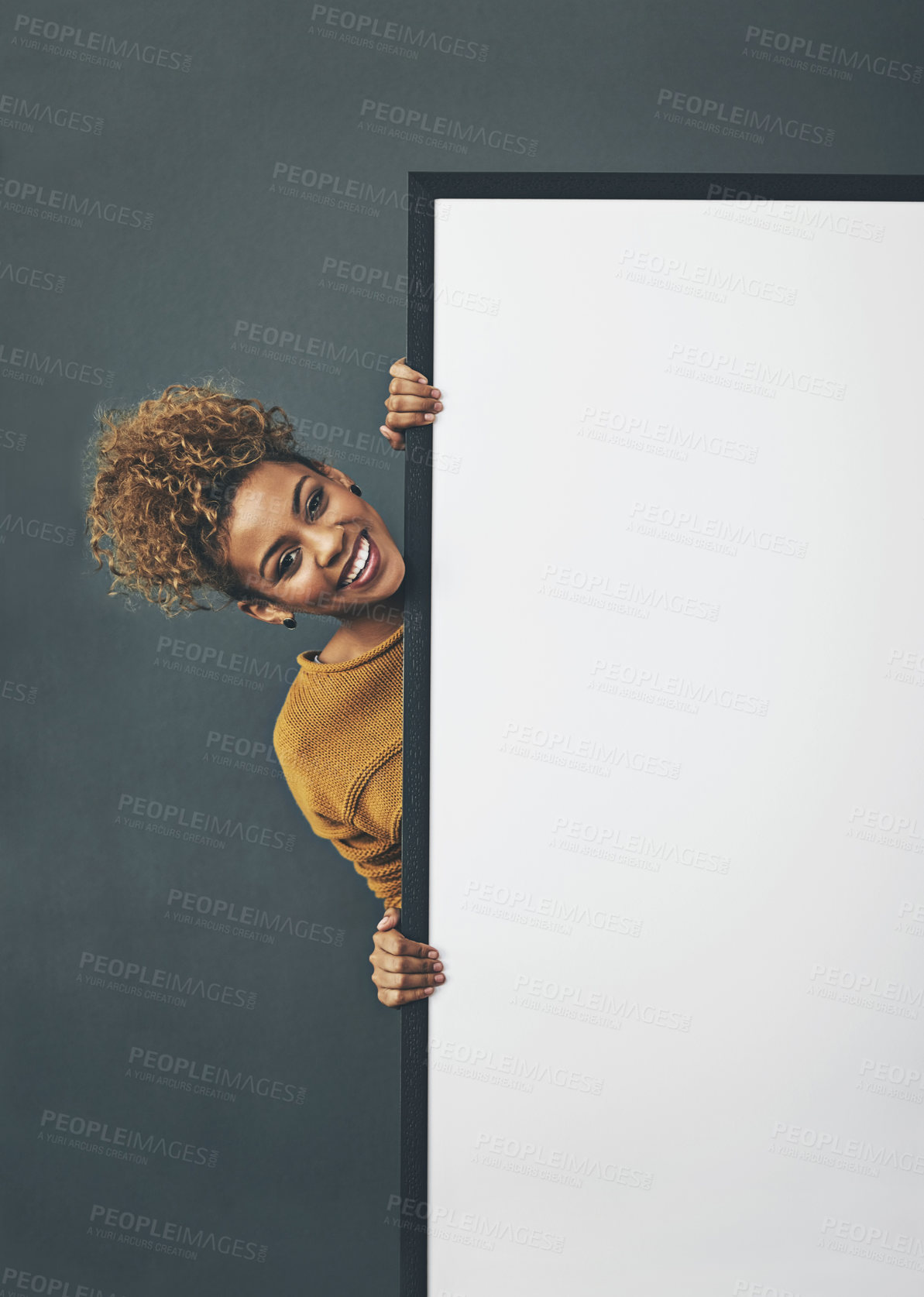 Buy stock photo Studio portrait of a young woman standing behind a blank sign against a grey background