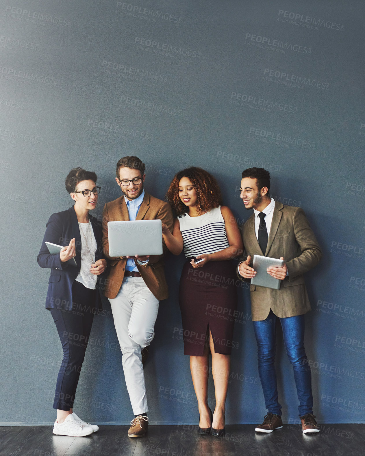Buy stock photo Studio shot of a group of businesspeople using wireless technology together while standing in line against a gray background