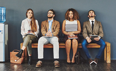 Buy stock photo Corporate business people looking tired, bored or nervous while waiting in line for an interview, meeting or training workshop. Anxious professionals, colleagues and coworkers sitting on a bench