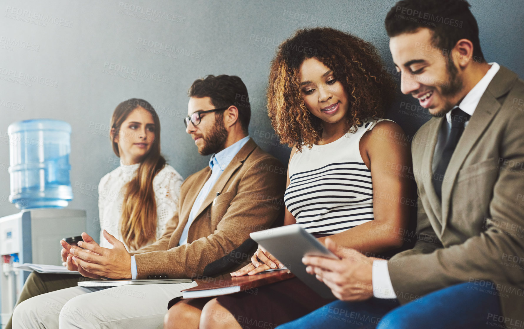 Buy stock photo Group of corporate business people in interview and talking while sitting in line, discussing with technology and networking. Diverse team, employees or adults on chairs in a row for a meeting