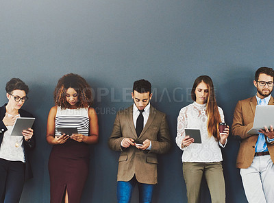 Buy stock photo Group or team of business people working and browsing with wireless technology in studio against a grey background. Digital marketing colleagues networking online to advertise a startup company
