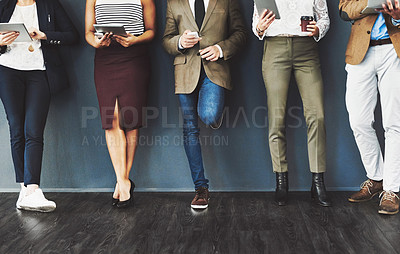 Buy stock photo Cropped studio shot of a group of businesspeople using wireless technology while waiting in line against a gray background