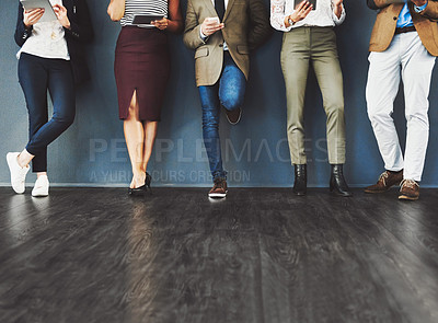 Buy stock photo Cropped studio shot of a group of businesspeople using wireless technology while waiting in line against a gray background