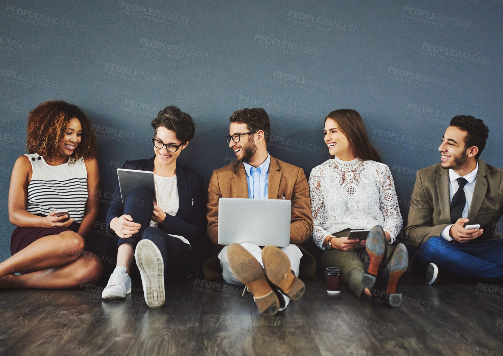 Buy stock photo Studio shot of a group of businesspeople using wireless technology and talking on the floor against a gray background