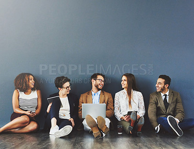 Buy stock photo Studio shot of a group of businesspeople using wireless technology and talking on the floor against a gray background