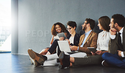 Buy stock photo Studio shot of a group of businesspeople using wireless technology and talking on the floor against a gray wall