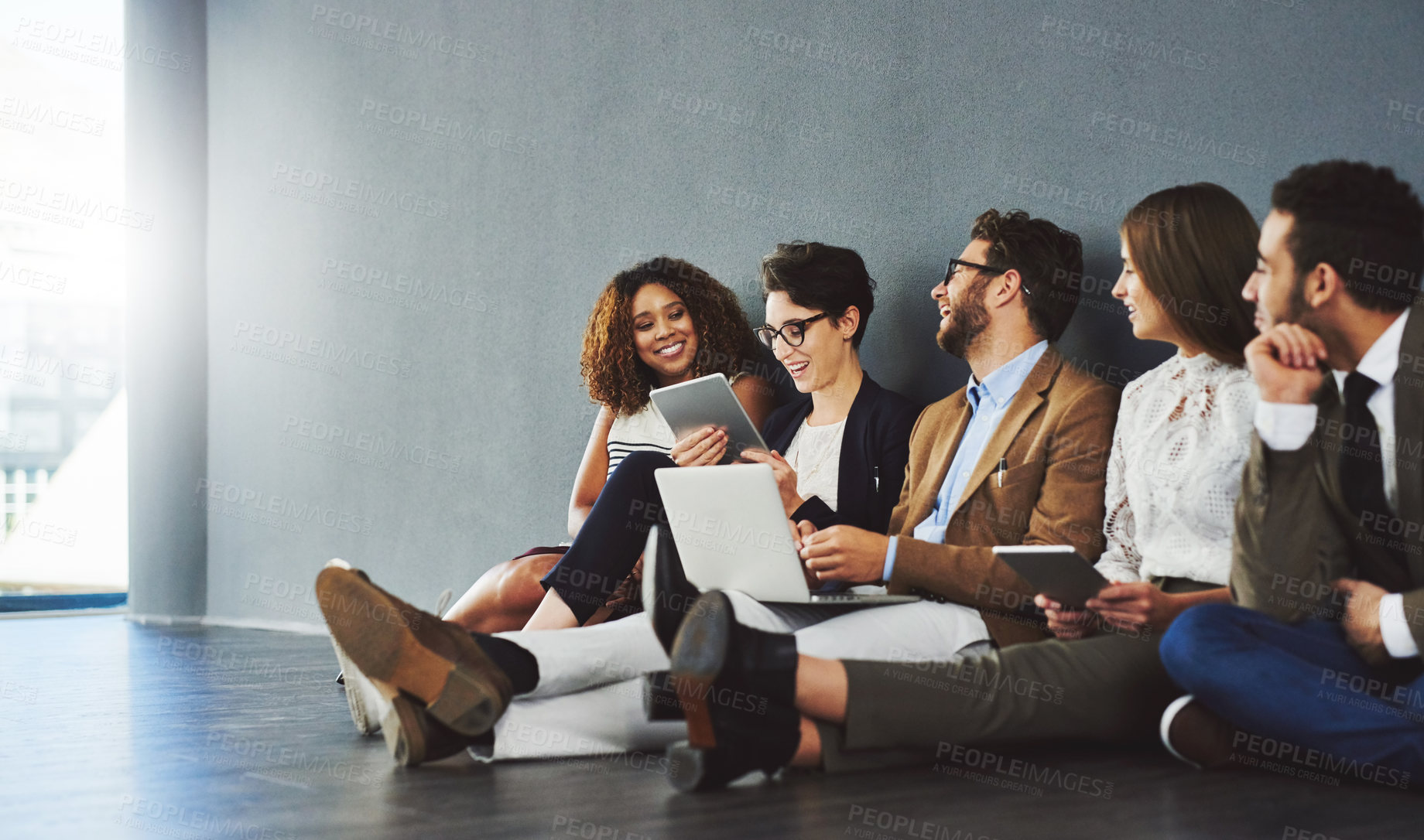 Buy stock photo Studio shot of a group of businesspeople using wireless technology and talking on the floor against a gray wall