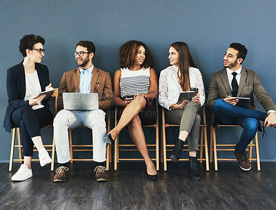 Buy stock photo Studio shot of a group of businesspeople using wireless technology and talking while waiting in line against a gray background