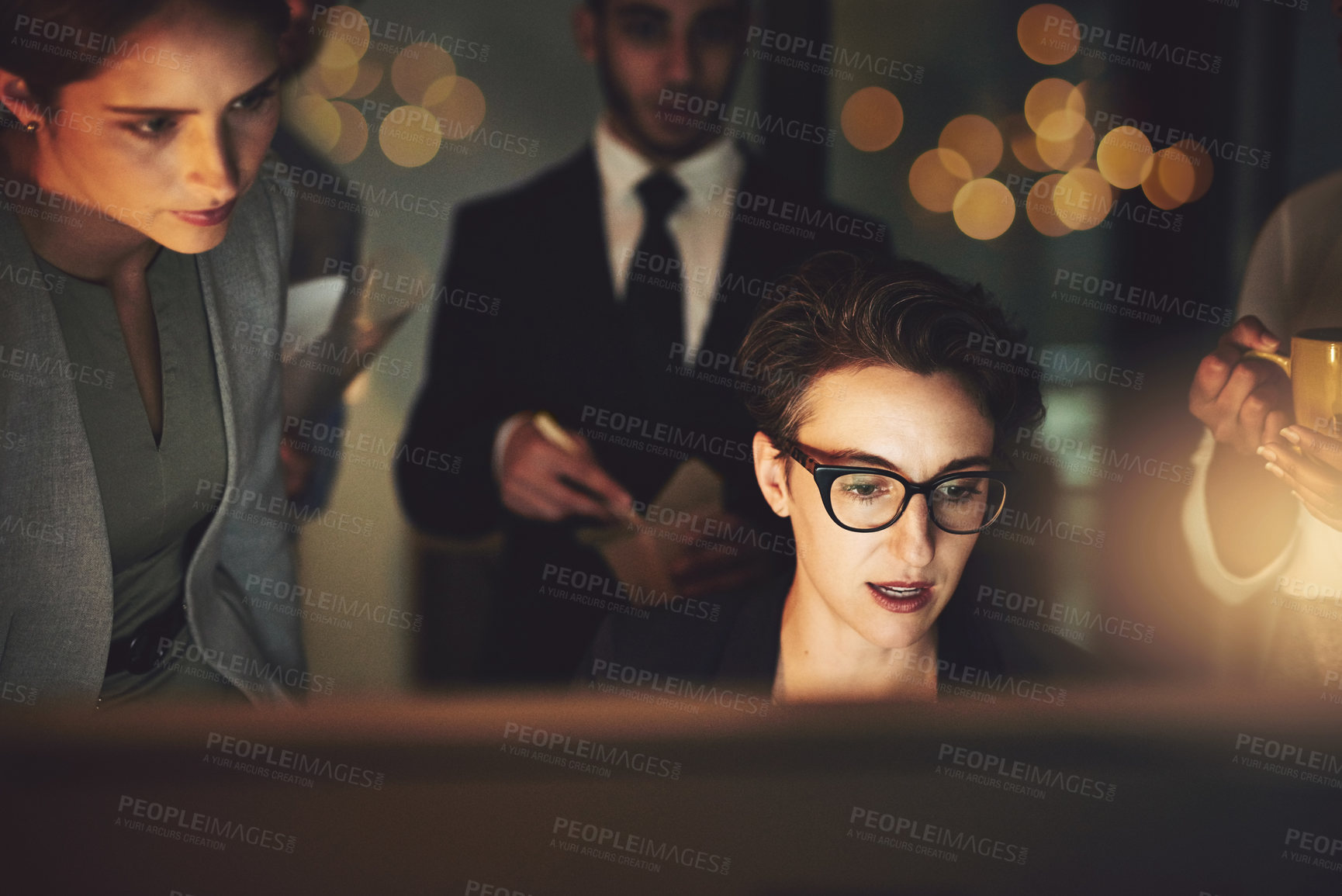 Buy stock photo Cropped shot of a young woman working late with colleagues standing in the background