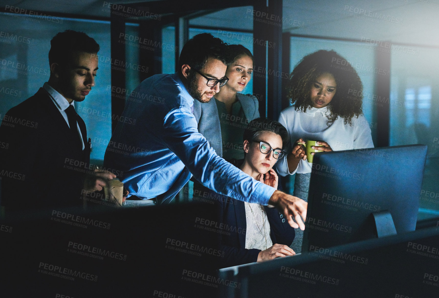 Buy stock photo Shot of colleagues standing together as they work on something on a computer at night