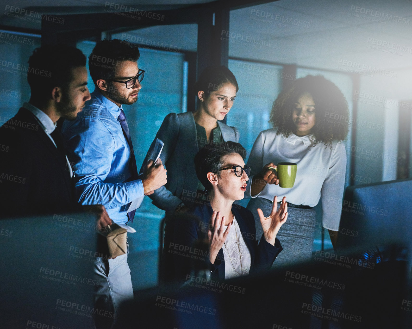 Buy stock photo Shot of colleagues standing together as they work on something on a computer at night