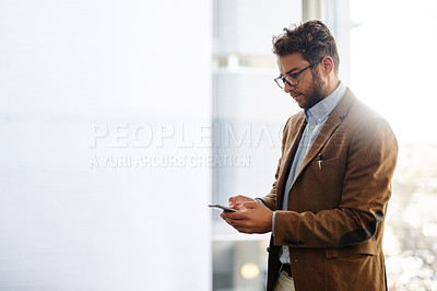 Buy stock photo Cropped shot of a handsome businessman using a mobile phone in his office
