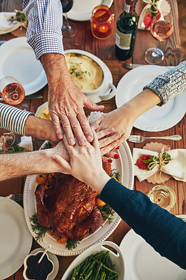 Buy stock photo High angle shot of a group of people piling their hands at a dining table