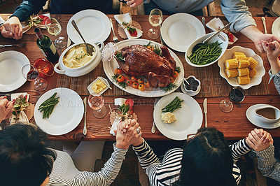 Buy stock photo High angle shot of a family saying grace at the dining table