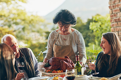 Buy stock photo Shot of a woman bringing a freshly cooked turkey to the dining table
