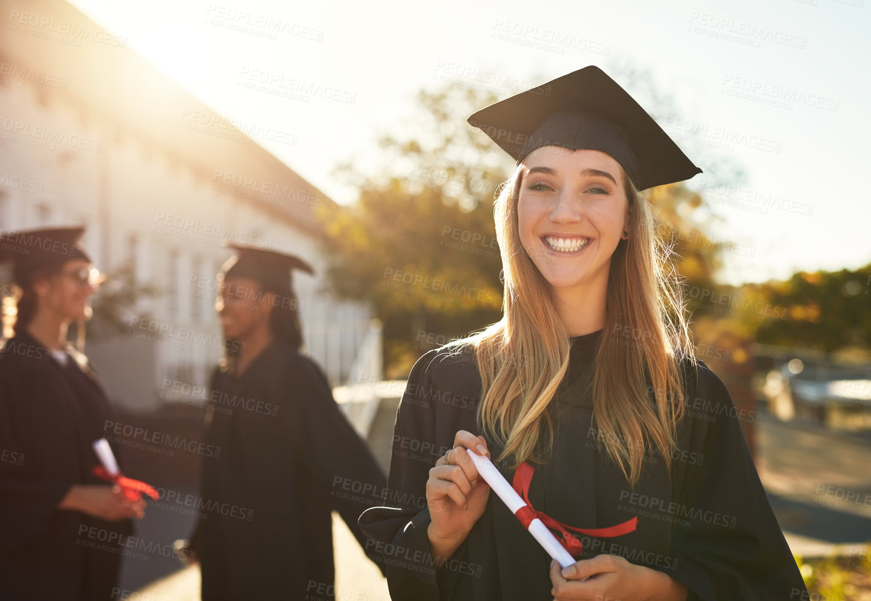 Buy stock photo Portrait of a happy young woman holding a diploma on graduation day