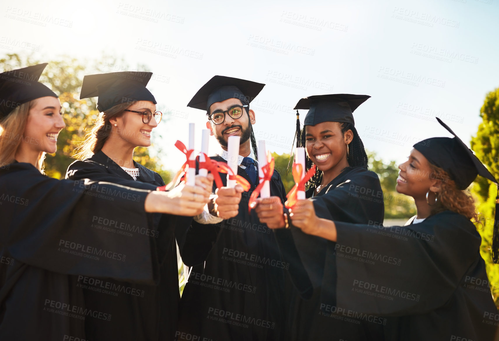 Buy stock photo Celebration, graduation and huddle of student friends outdoor on campus together for ceremony or event. Diversity, education or future and smile of happy graduate people cheering for group success