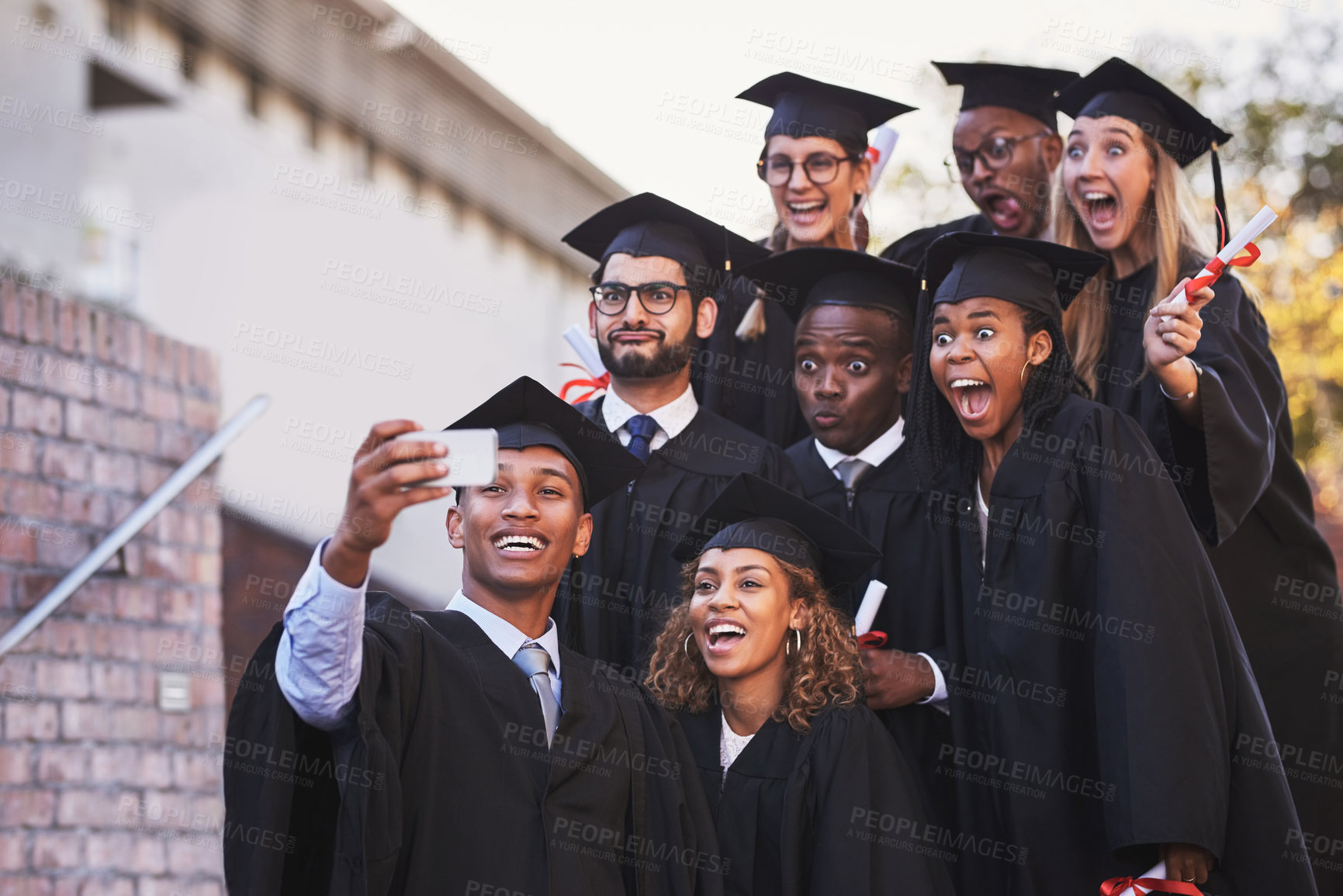 Buy stock photo People, selfie and graduation or smile on campus, memory and picture for silly graduate or diploma. Funny face, students and university achievement or social media post, scholarship and celebration