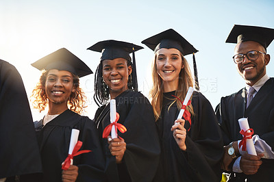 Buy stock photo Shot of a group of university graduates holding up their diplomas