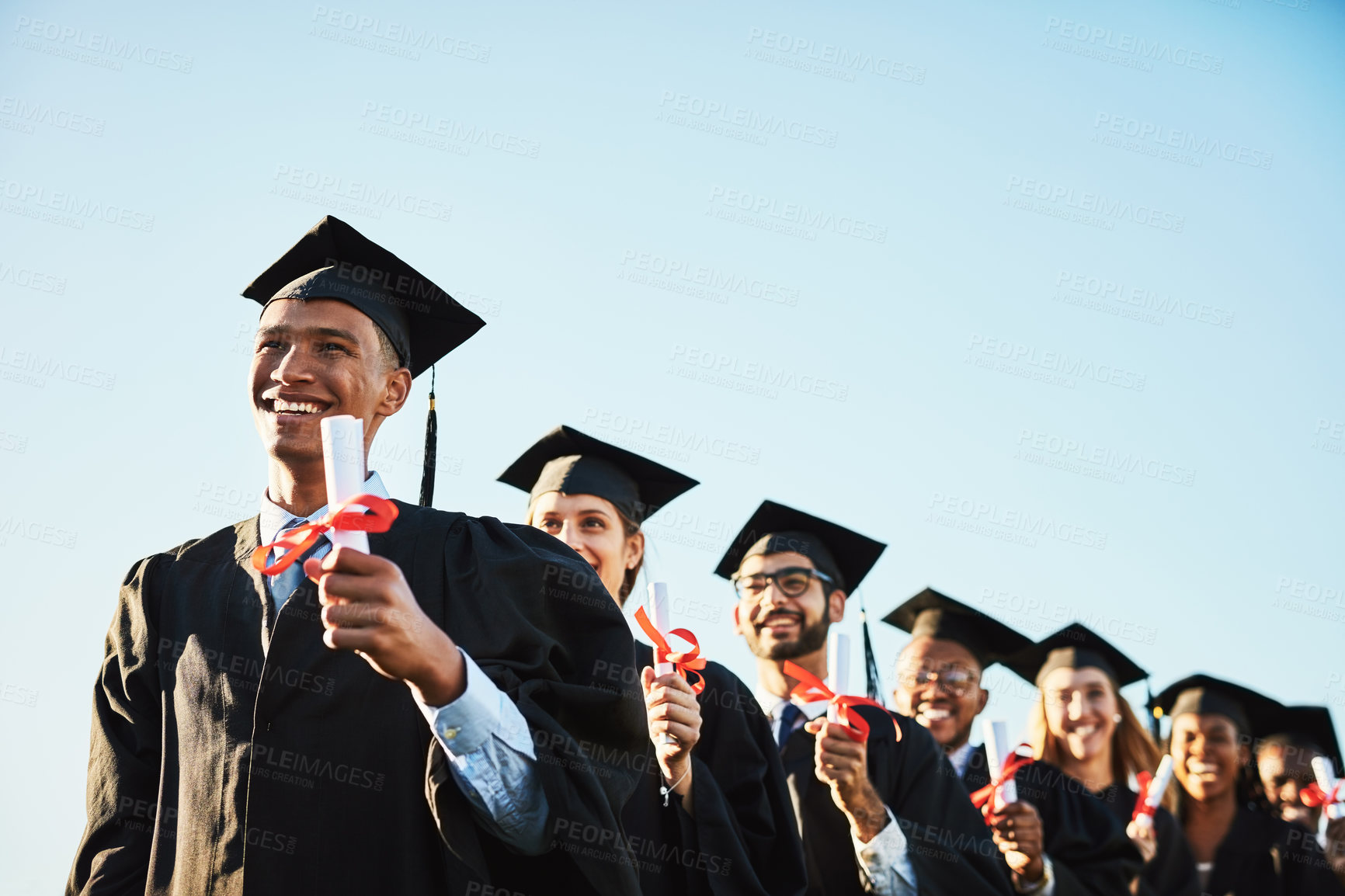 Buy stock photo Shot of a smiling university student on graduation day with classmates in the background