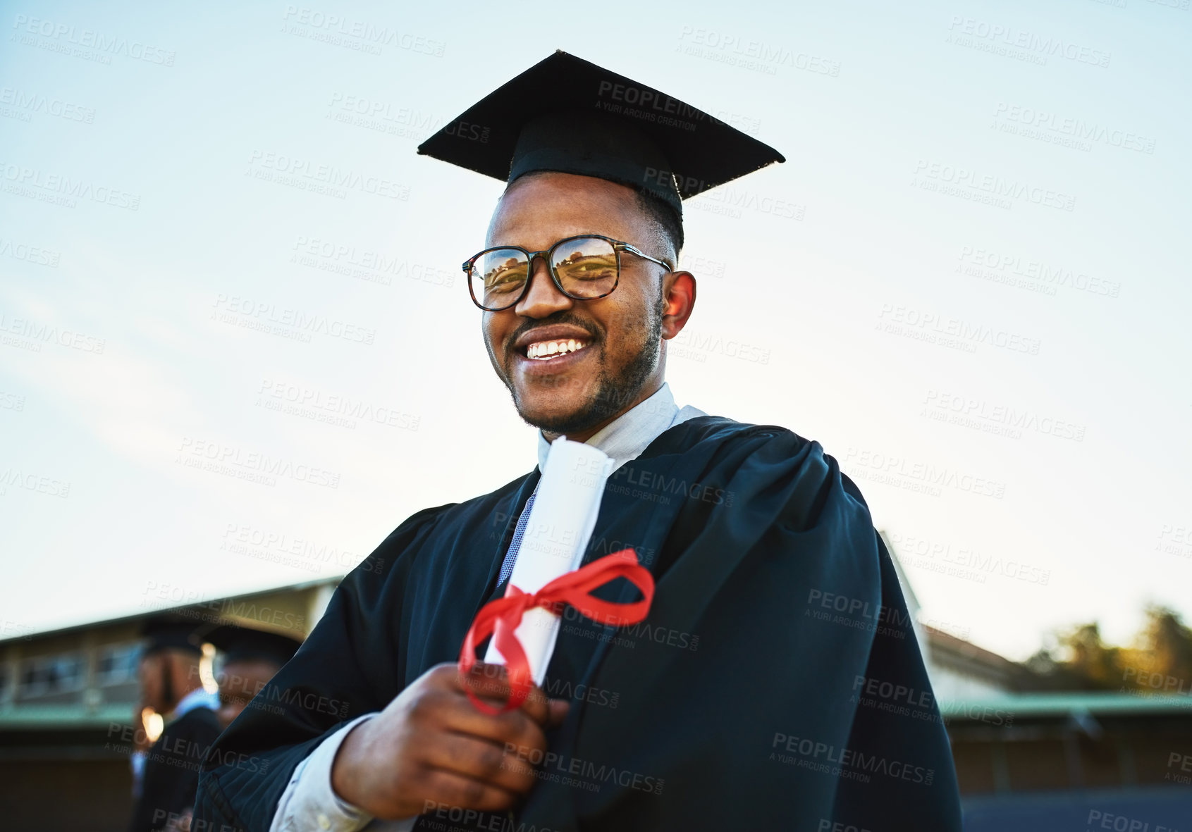 Buy stock photo Portrait of a confident young man holding a diploma on graduation day