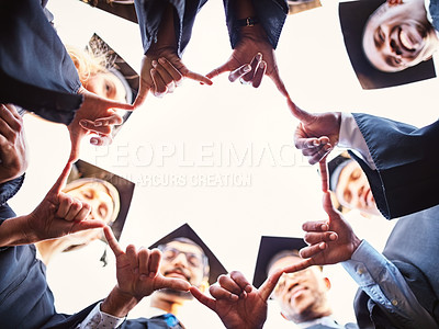 Buy stock photo Low angle shot of a group of young students joining their hands together on graduation day